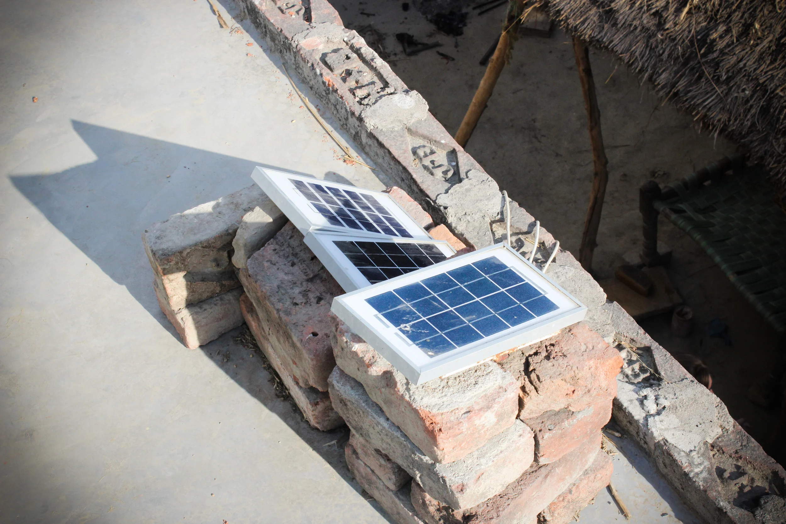 The panels were propped up on bricks without brace or support. The shadows reveal that they are not facing the sun, and the taller stack is over-shadowing the lower panels, revealing very ineffective, poor planning or implementation. 