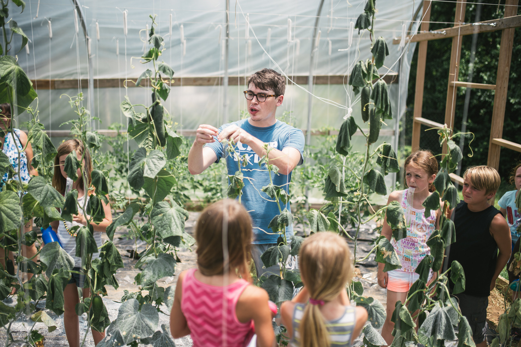 Bryan Sanders, Camp Skillz counselor and consistent community garden volunteer, explains pole beans to campers who get to work in the garden throughout the summer. 