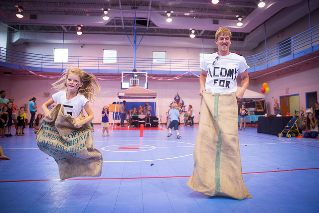 Rylan Aaseby and his daughter, Ezrah, compete in family relays during our back to school celebration. The family had matching shirts that together read "We Love the Academy for G.O.D."