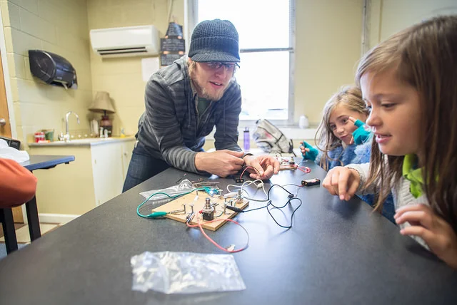 In Exploratory Hour, there's no limit to the challenges students undertake. Here, Academy teacher Skylar Aaseby has kids building light circuits in both series and parallel configurations with batteries and switches.