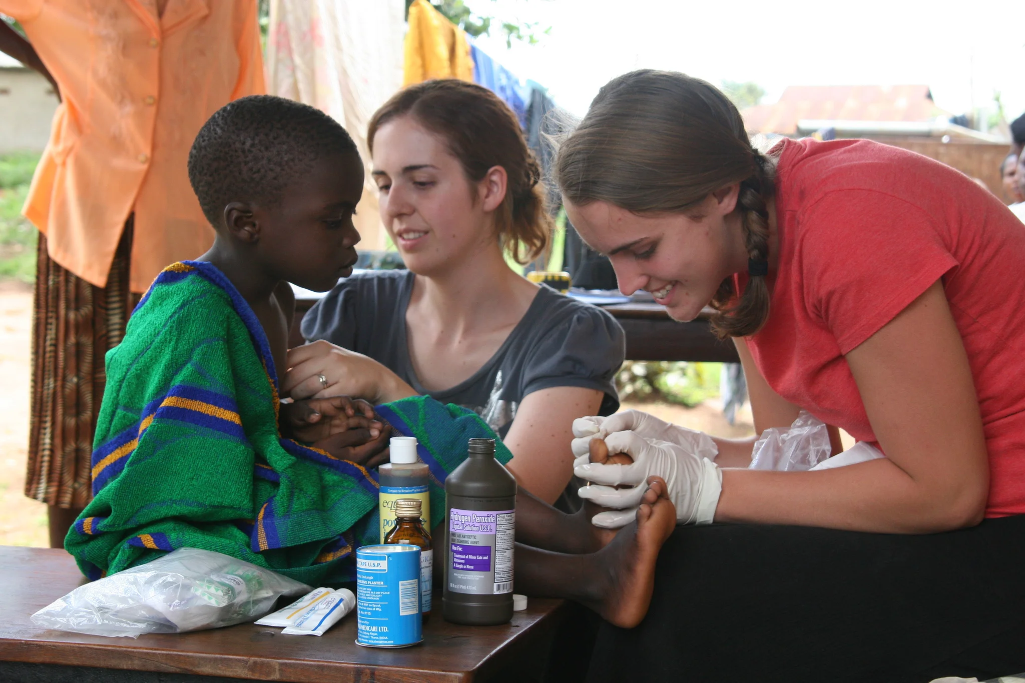 Ashley Moore and Celesta Bargatze perform wound care on a child's foot. You can find pictures of this same young boy today, below. 