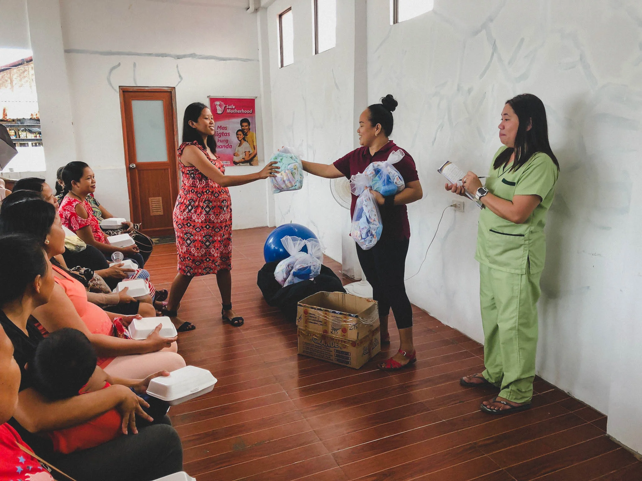Rina Miller and Nerissa, a midwife at Cumpio Clinic, share necessary supplies with the mothers who attended the conference, helping them to get the start they deserve with adequate supplies.