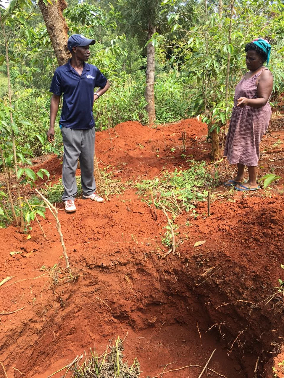 Simon shares with a neighbor the process of adding compost to the pit.