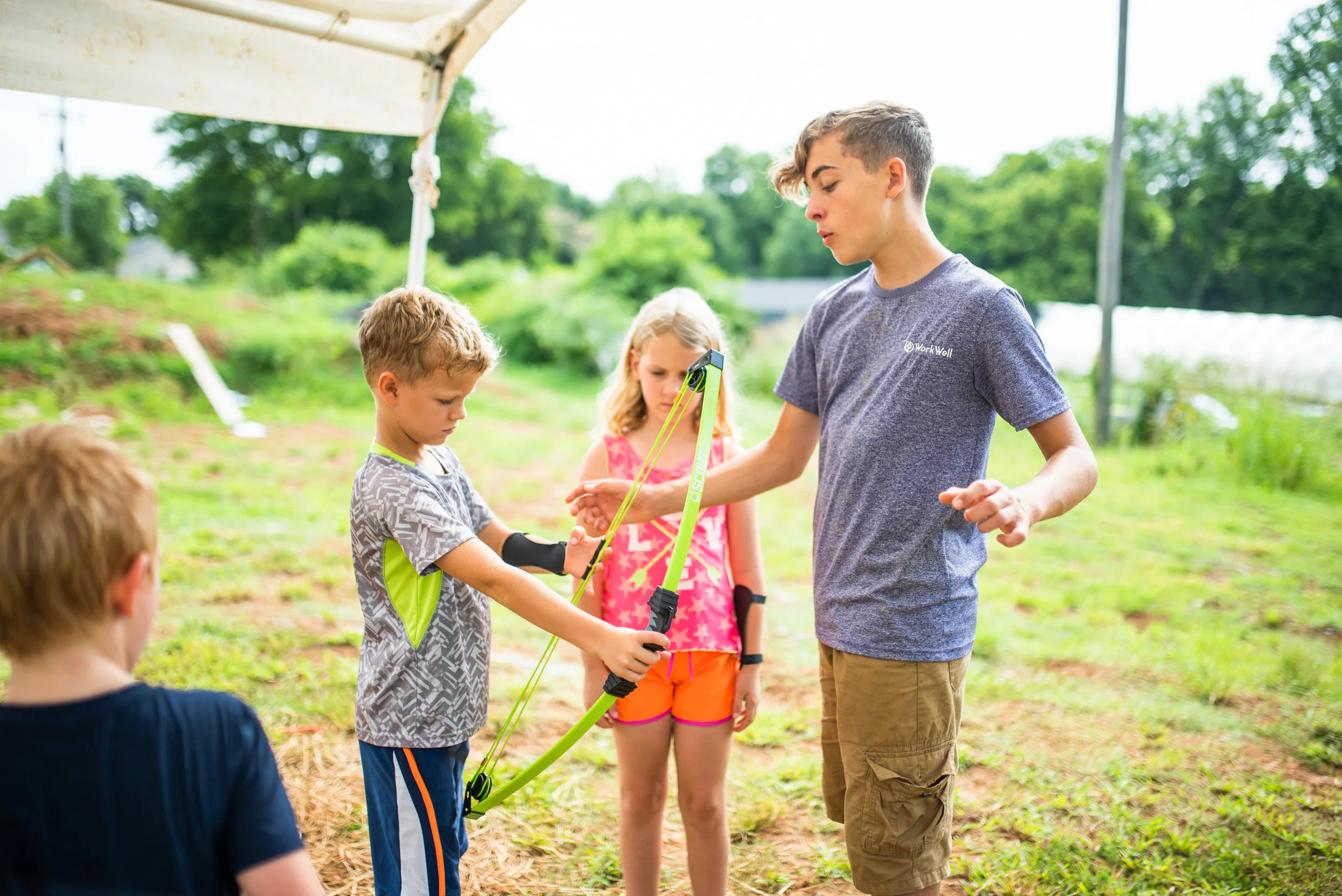 River Riechert helps campers at Camp Skillz learn how to do archery during their “Survivor Island” week.