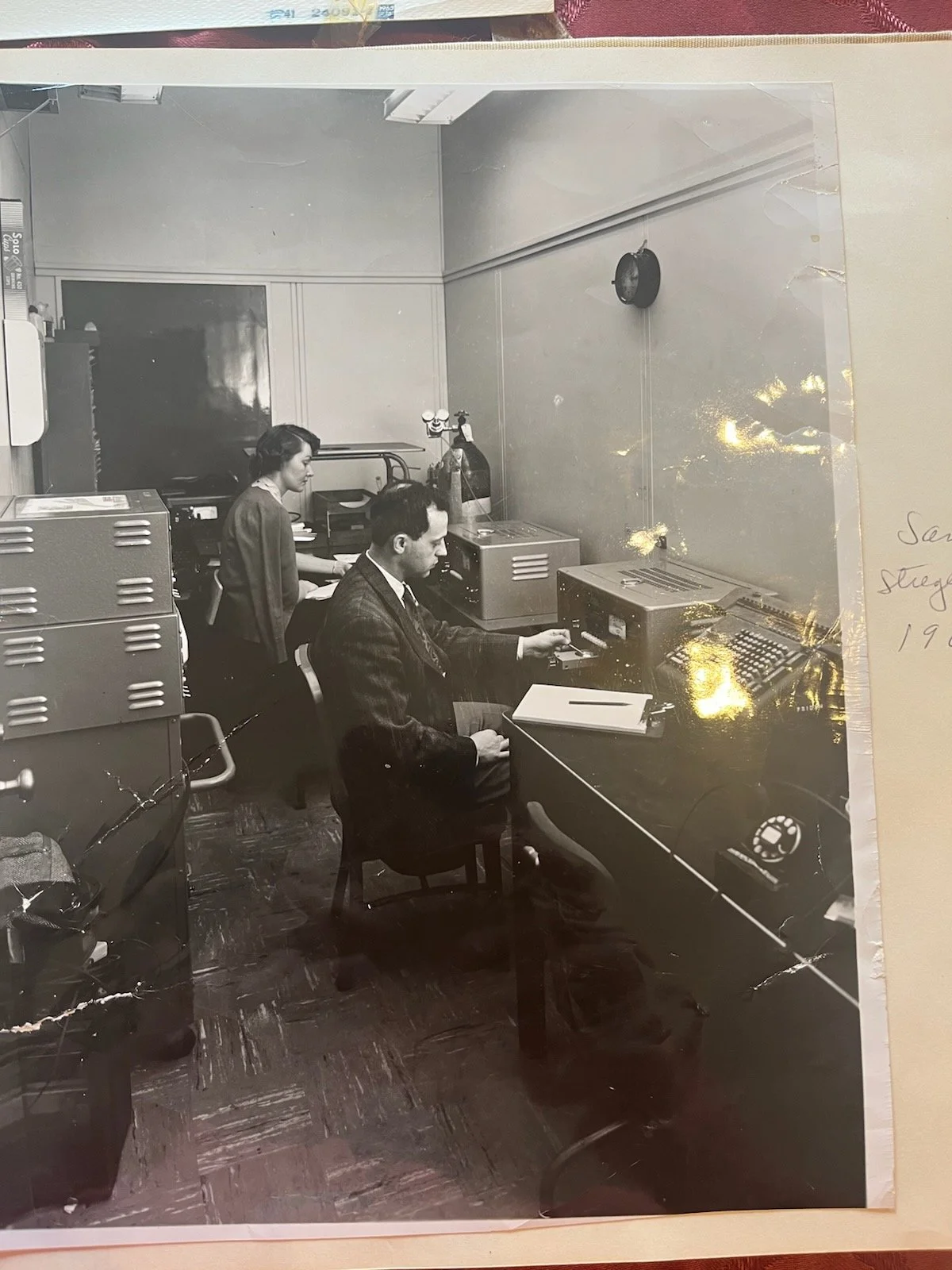 Sam Stregevsky in a suit, seated in an office credenza in or around 1953.