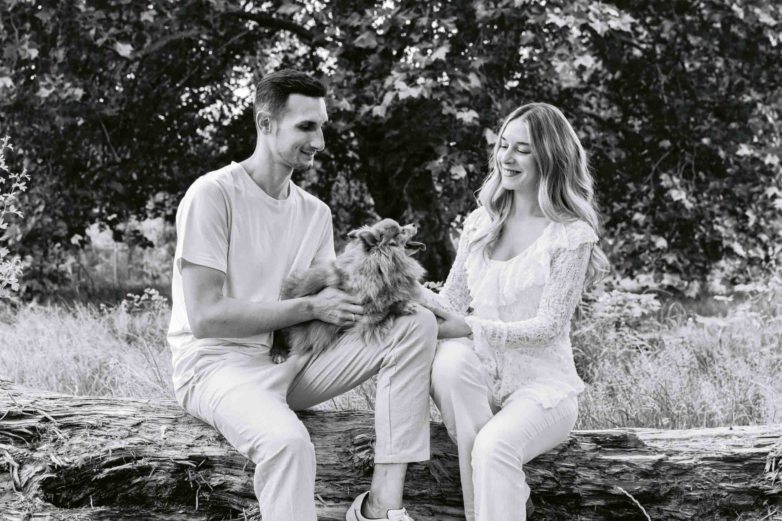 A couple and their dog having a cuddle on a log during an outdoor photo session on Clapham Common