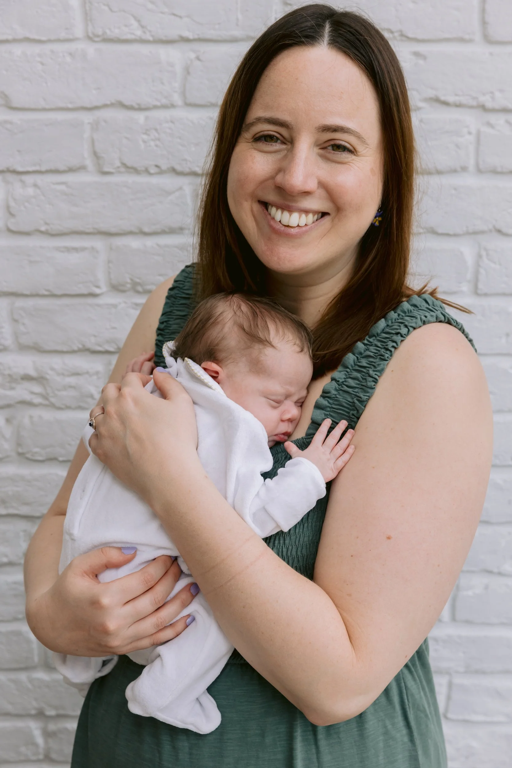 Mum holding a newborn baby and smiling during a newborn photo shoot in London