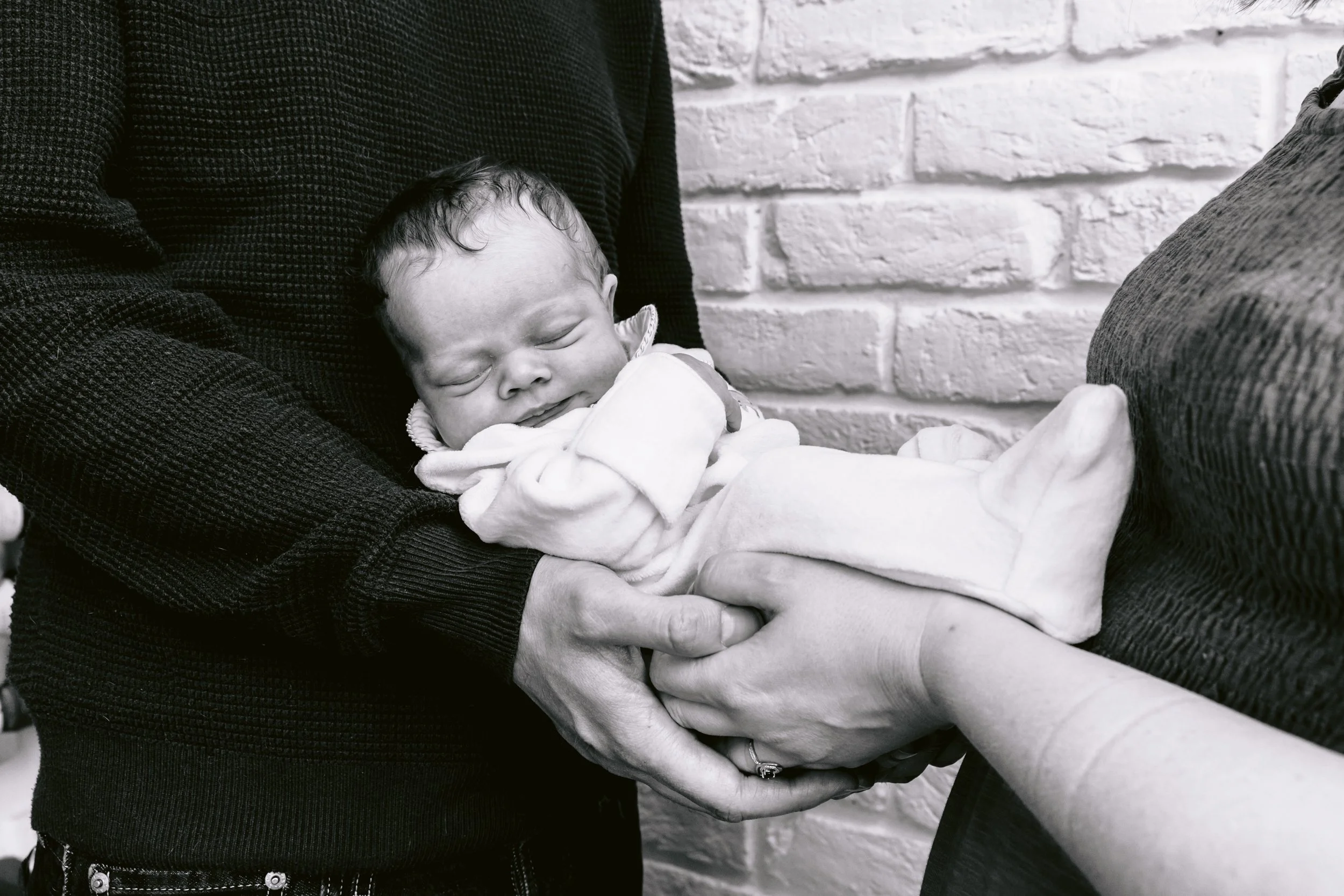 Mum and dad holding a sleeping newborn baby