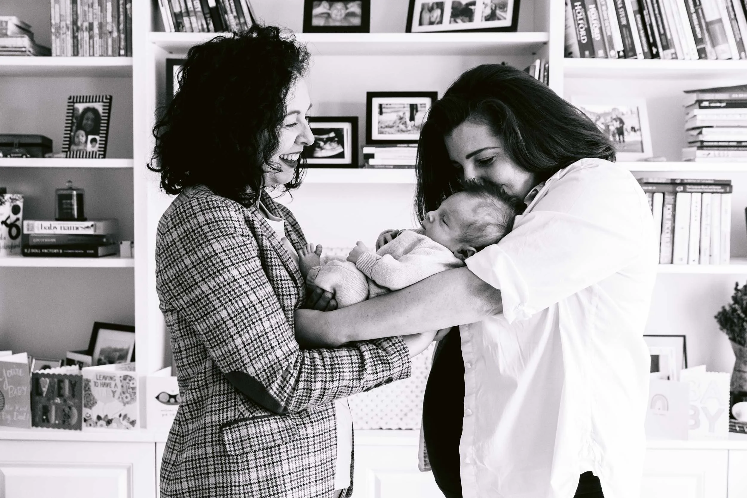Mothers kiss and cuddle their newborn baby during a family photoshoot in North London