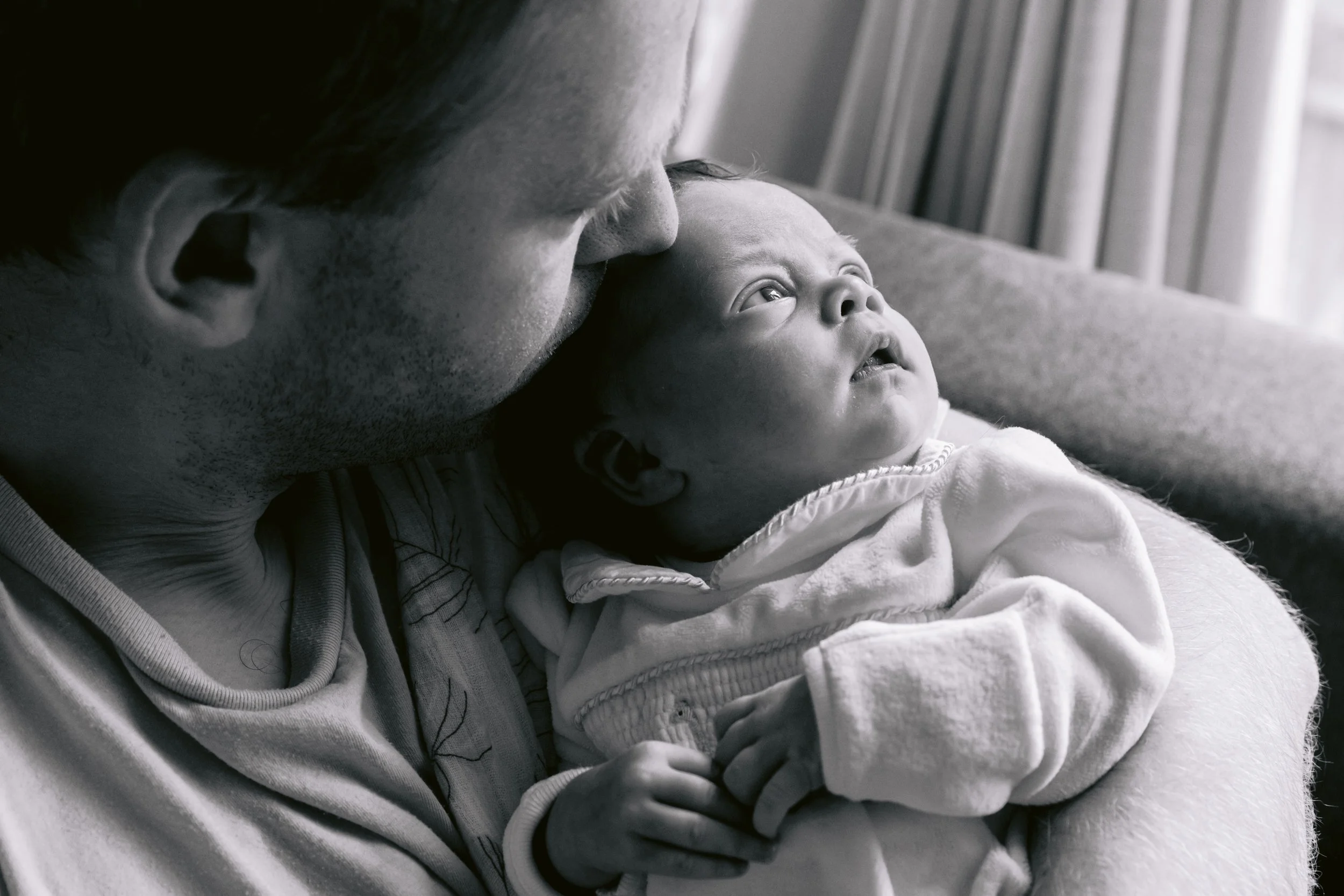 Dad kisses newborn baby during a photo session in South West London