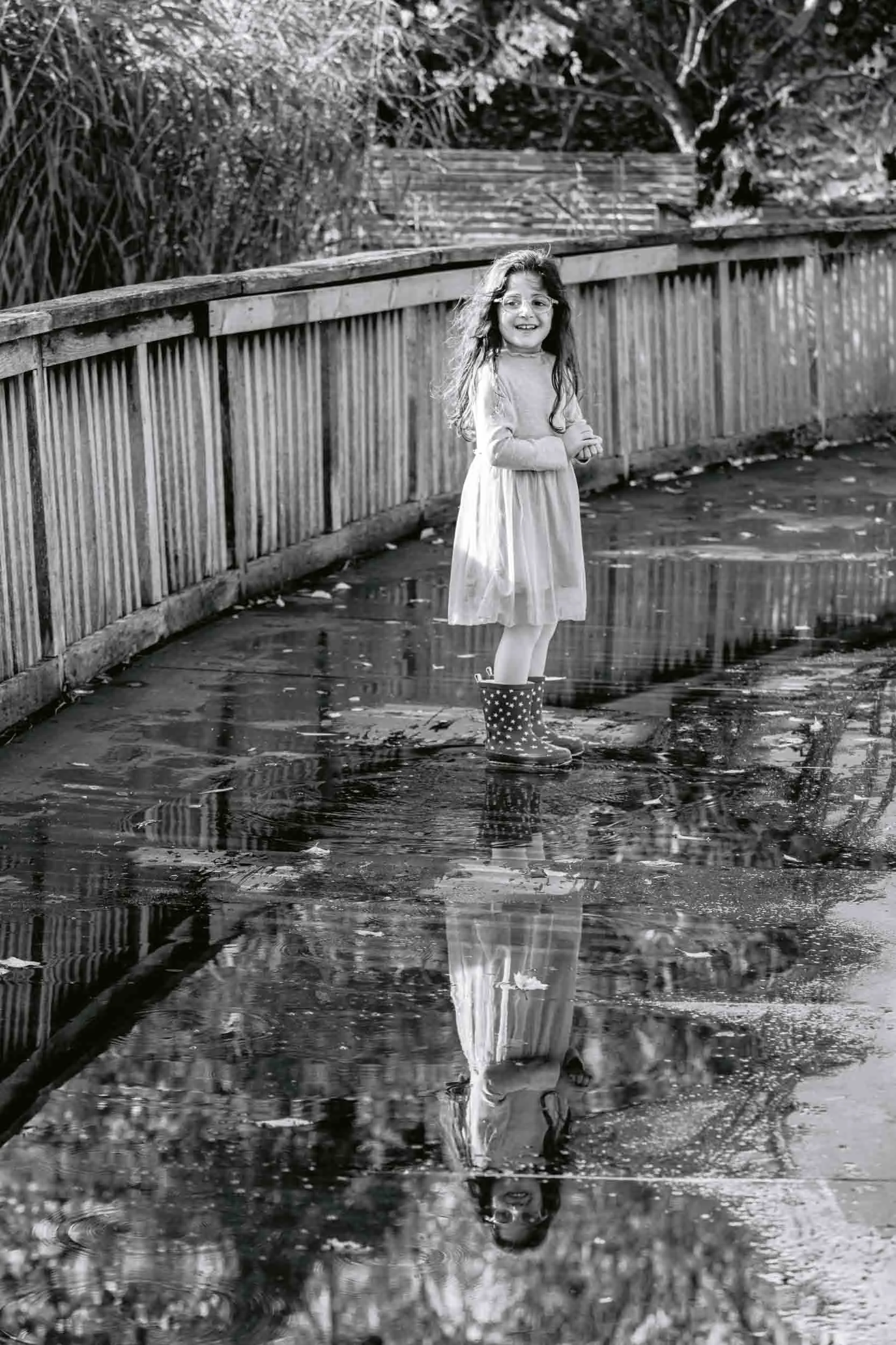 Girl looks back at her parents while crossing a bridge in Regents park during a family photoshoot
