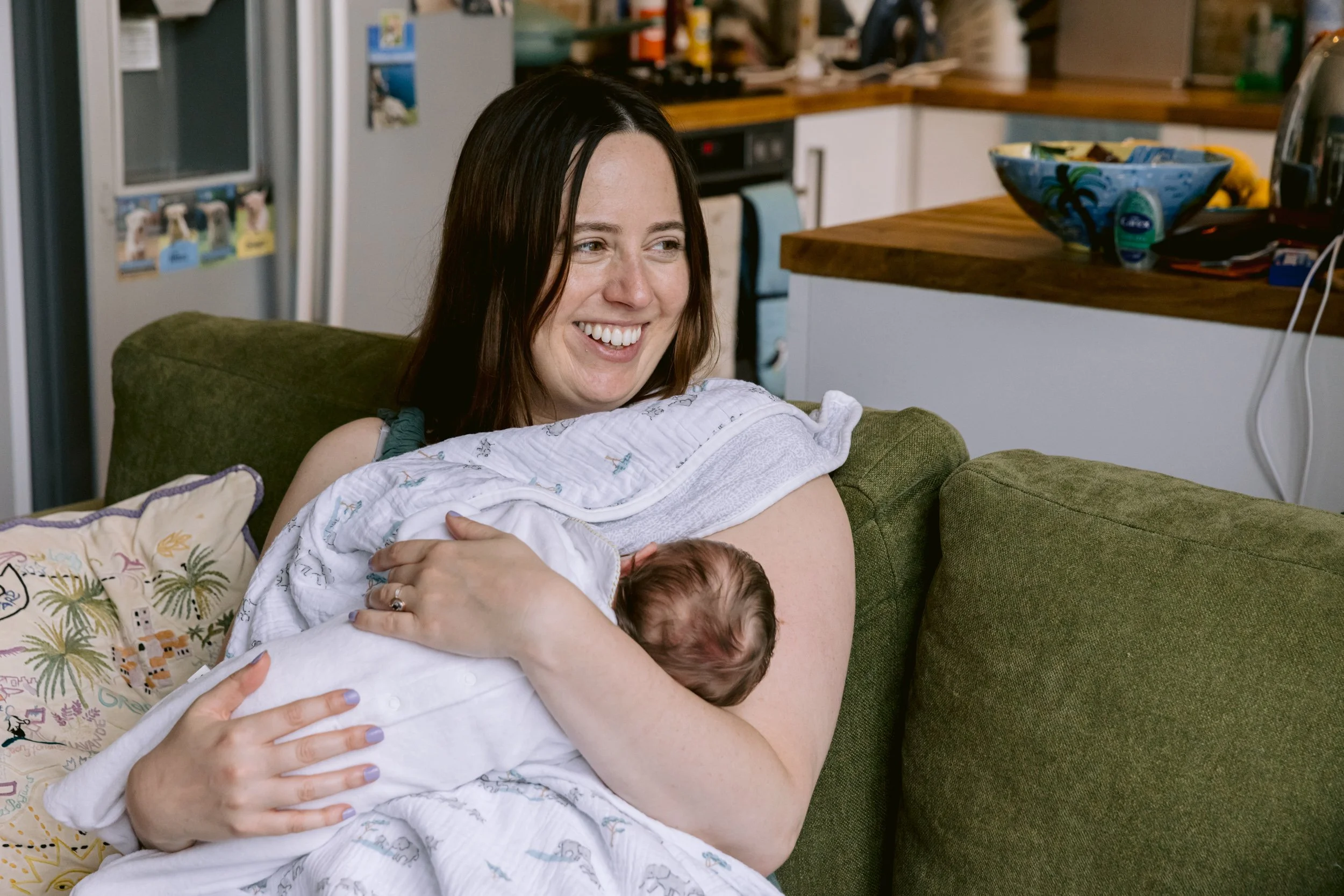 Mum smiling while breastfeeding a newborn baby during a newborn photography session in Putney