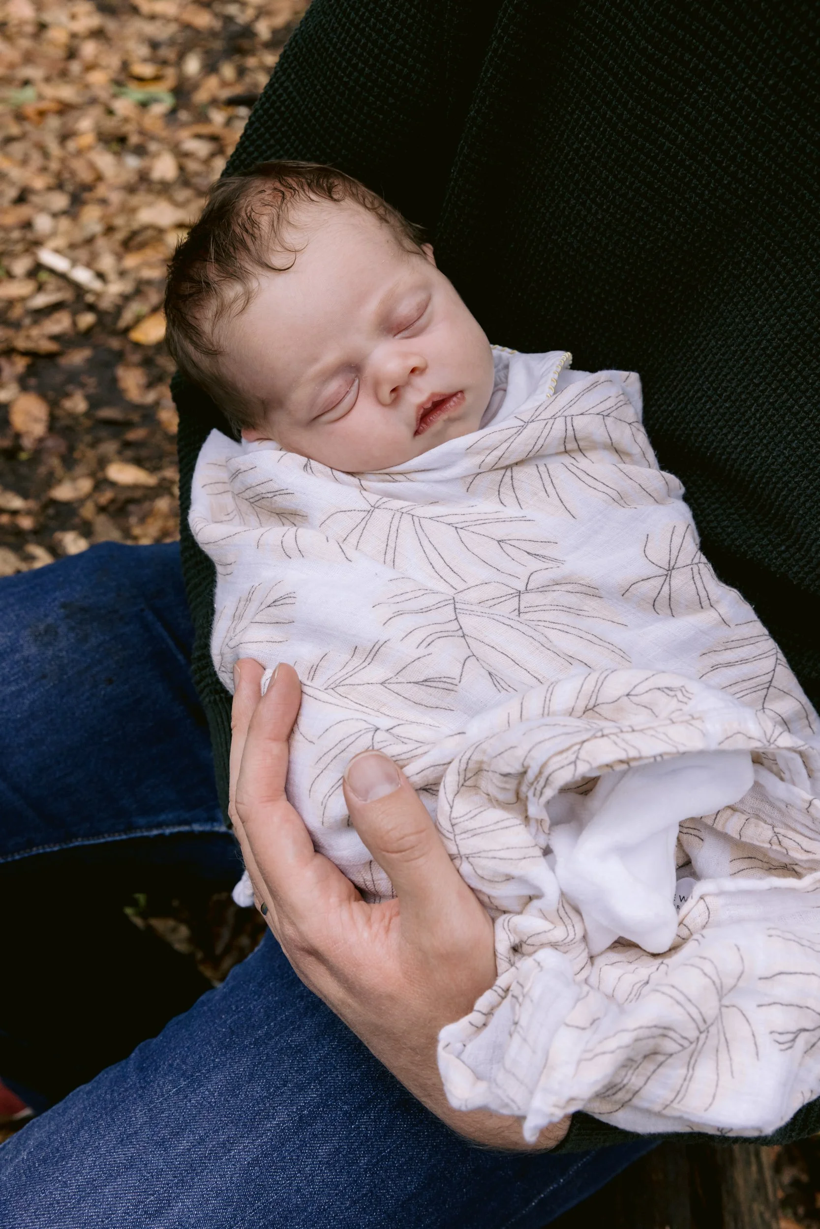 Baby sleeping in dad's arms during an outdoor newborn session in London