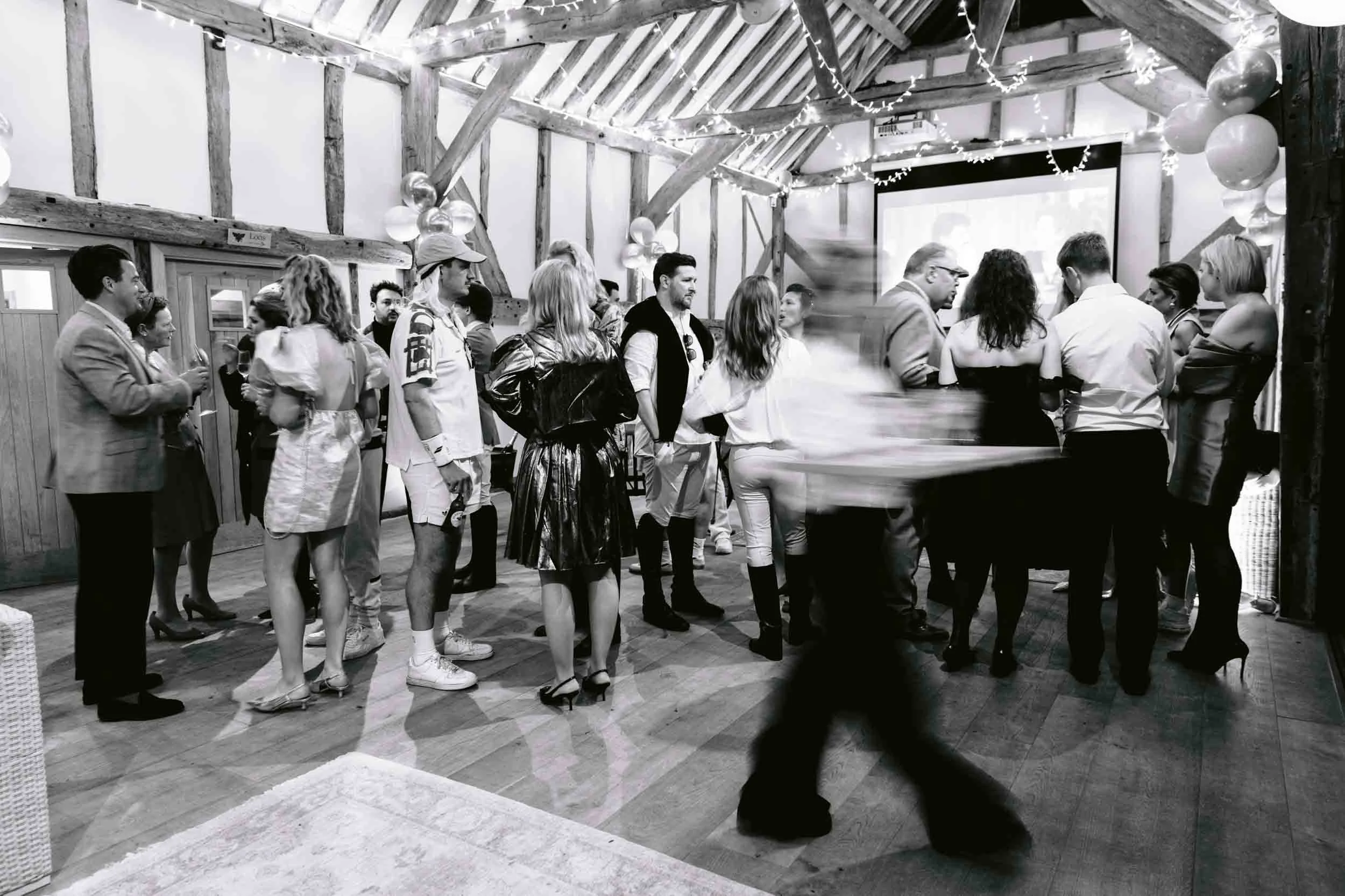 A slow shutter speed for capturing catering moving through a room filled with guests mingling at a party at Somersbury Barn in Surrey