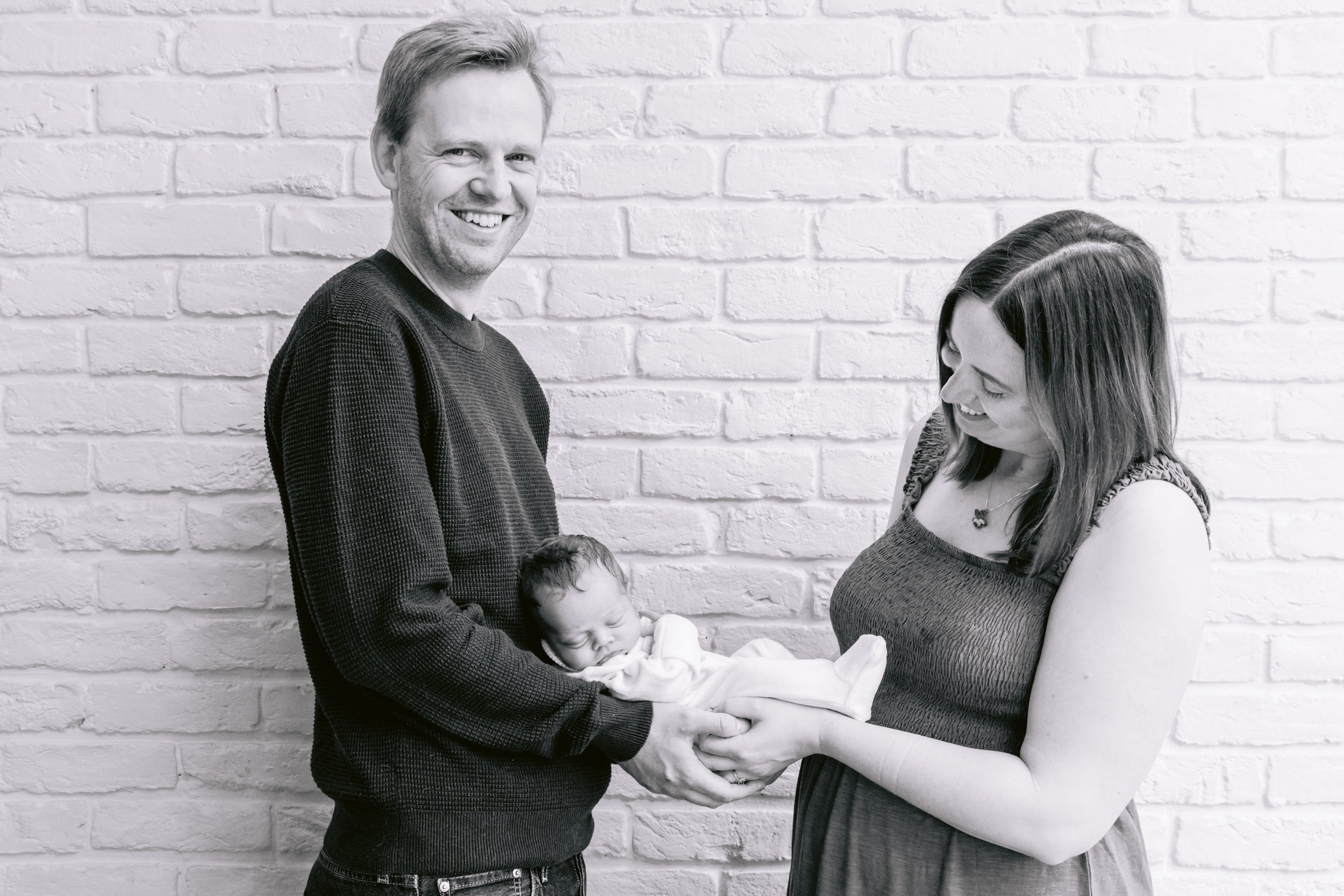 Mum and dad holding a newborn baby during a photo session in South West London