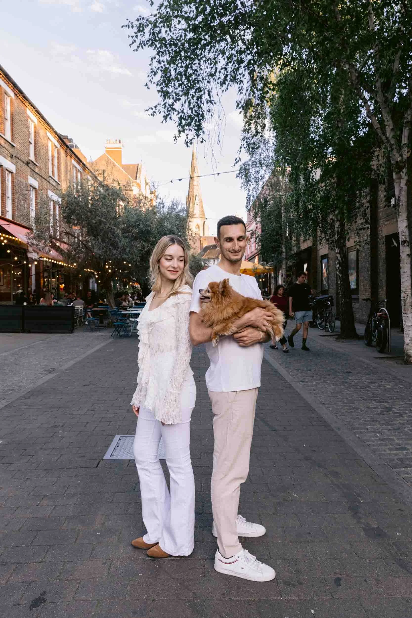 Couple standing in a street in Clapham Common holding their pomeranian