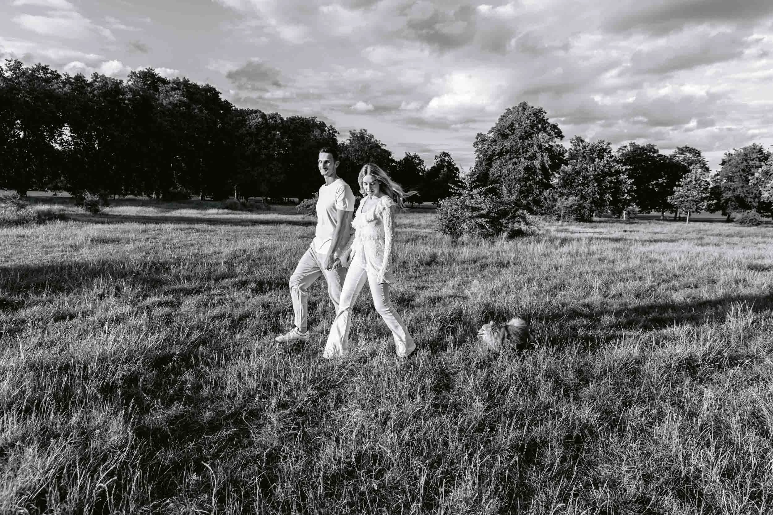 Couple and dog walking on Clapham Common during golden hour