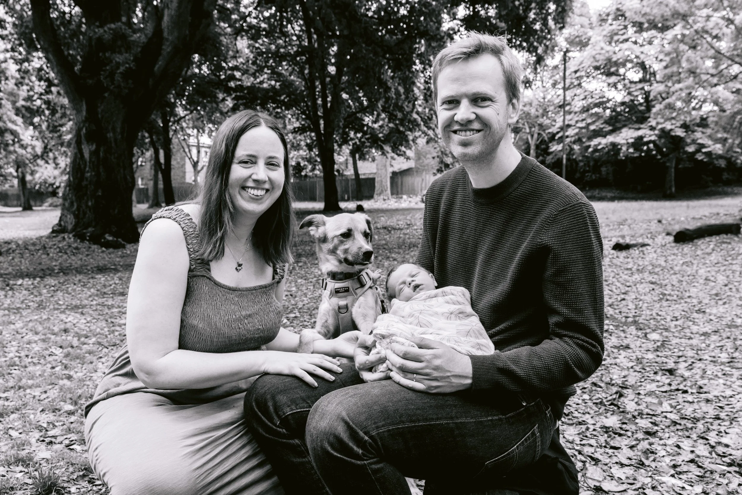 Family enjoying a quiet moment with their newborn baby and their dog in a Putney park
