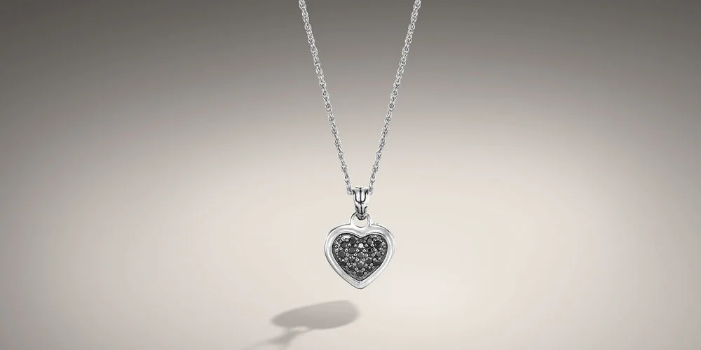 John Hardy black sapphire pave heart pendant. The pendant sits on an 18 inch link chain. The heart has hand woven silver around the outside and 18 pave set black sapphires in the center.
