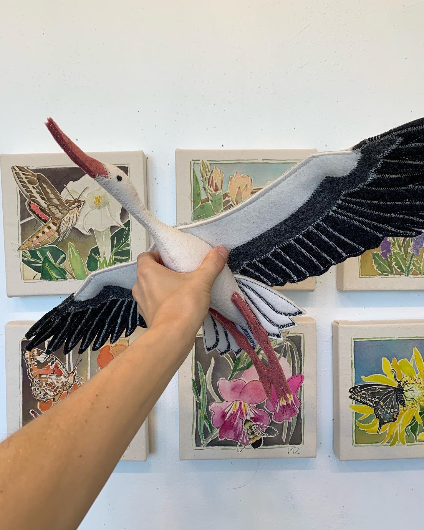 Felt white stork for baby mobile in front of artworks for my upcoming show &ldquo;where the flowers sing&rdquo; @howyoureside in #santafenewmexico opening Friday, May 19th, 4-7pm