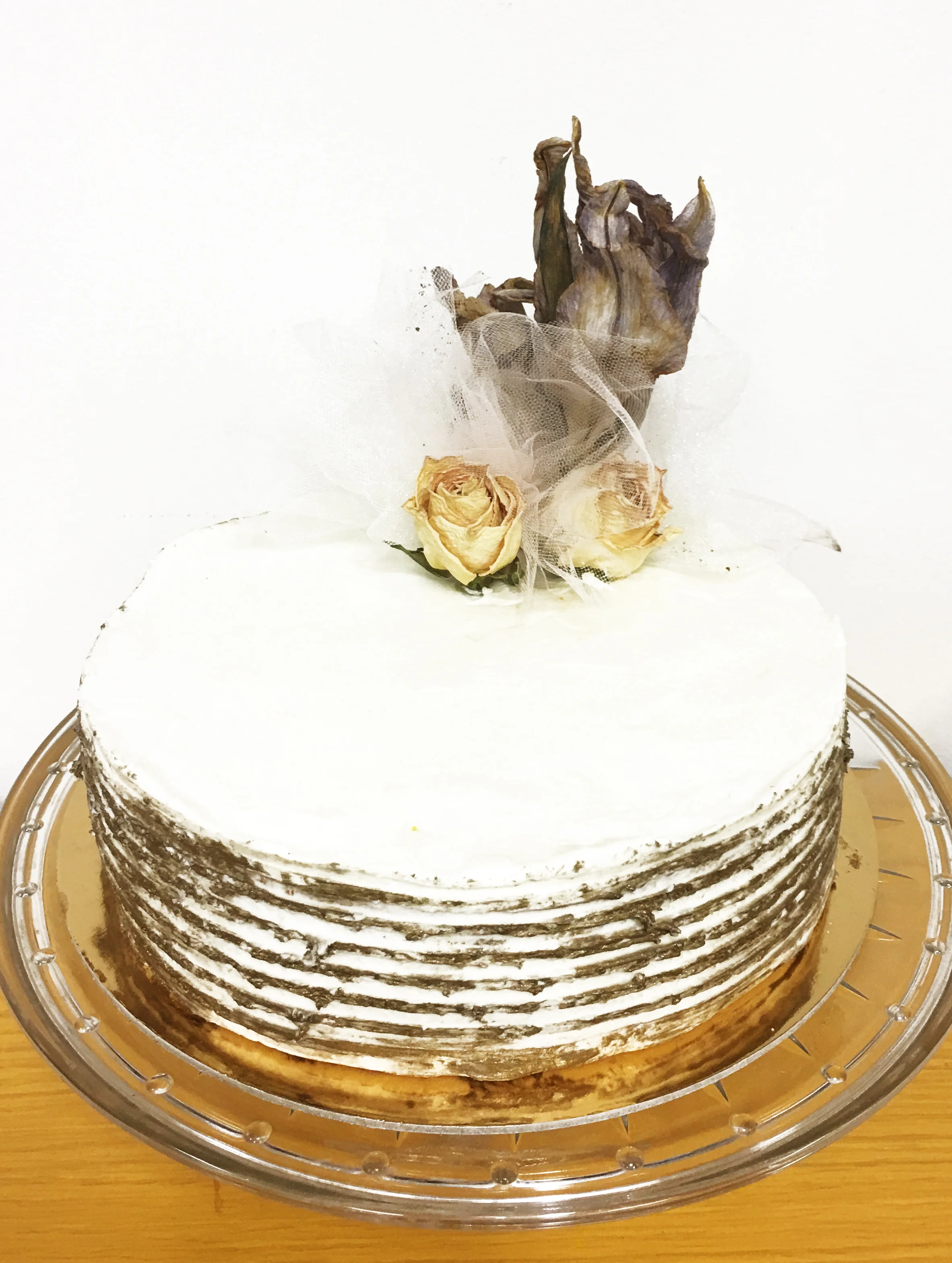    The House of Mirth  by Edith Wharton   Two layers of pristine white cake filled and frosted (suffocated) with rose-perfumed (Rosedale) Swiss Meringue Buttercream. The sides show damage beneath the gilded facade. On top rest, sprigs of dried (dead)