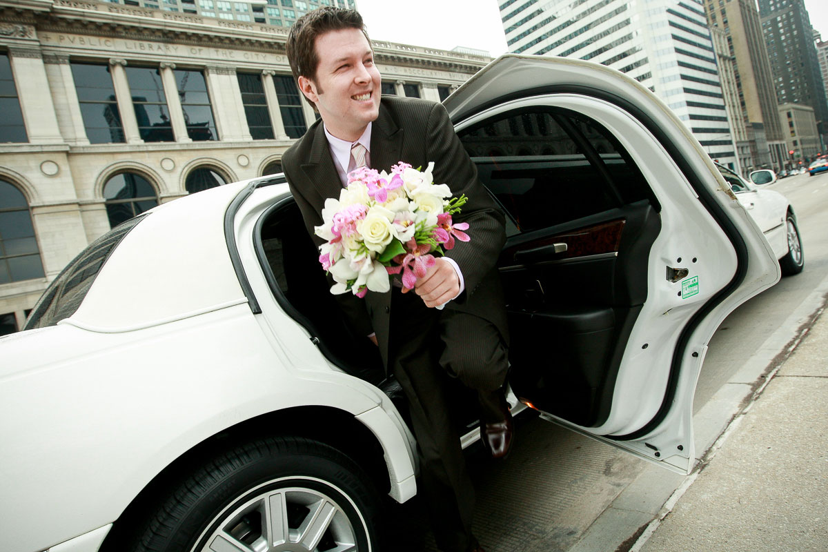 Groom holds the bouquet as he exits the limo at Millennium Park Chicago. 