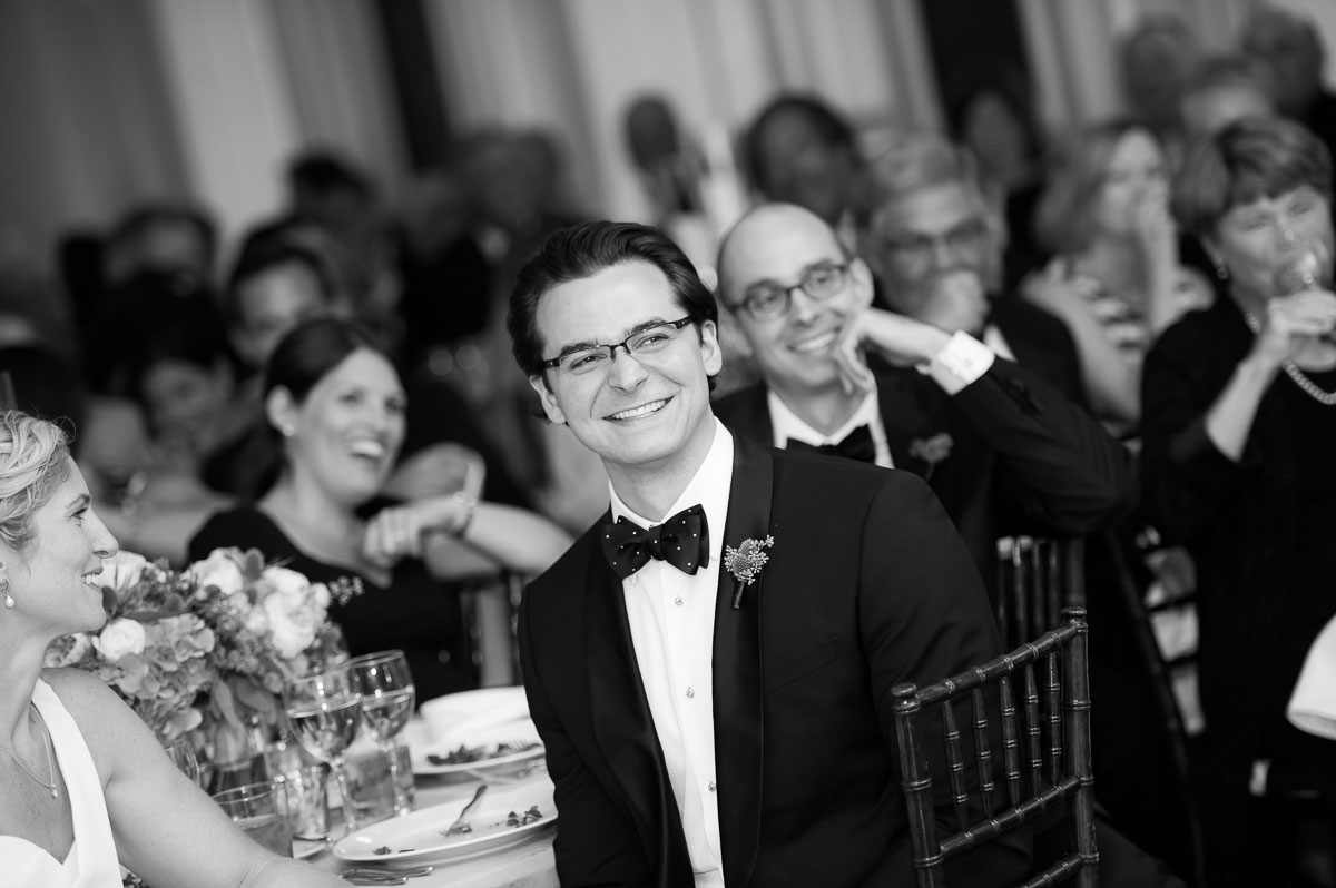 Groom laughs during the best man toast at his Chicago History Museum wedding reception. 