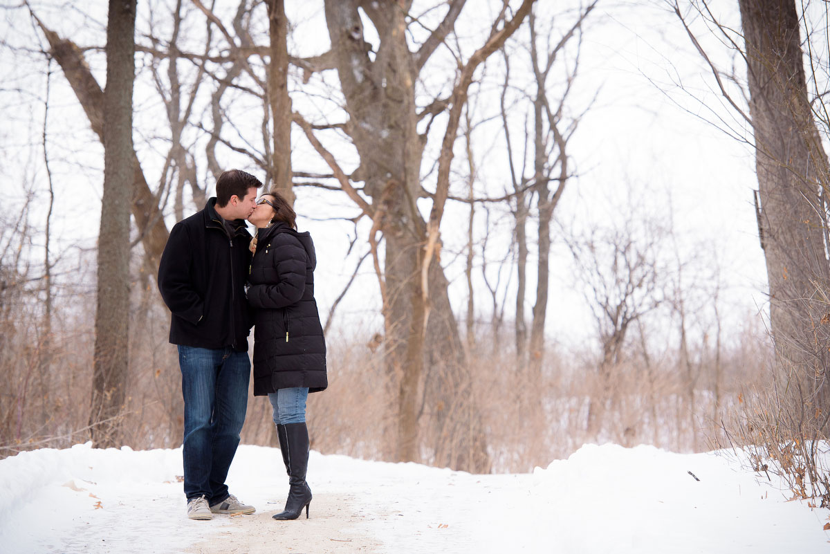 The couple pauses for a kiss during their winter engagement session at Deicke Park in Huntley. 