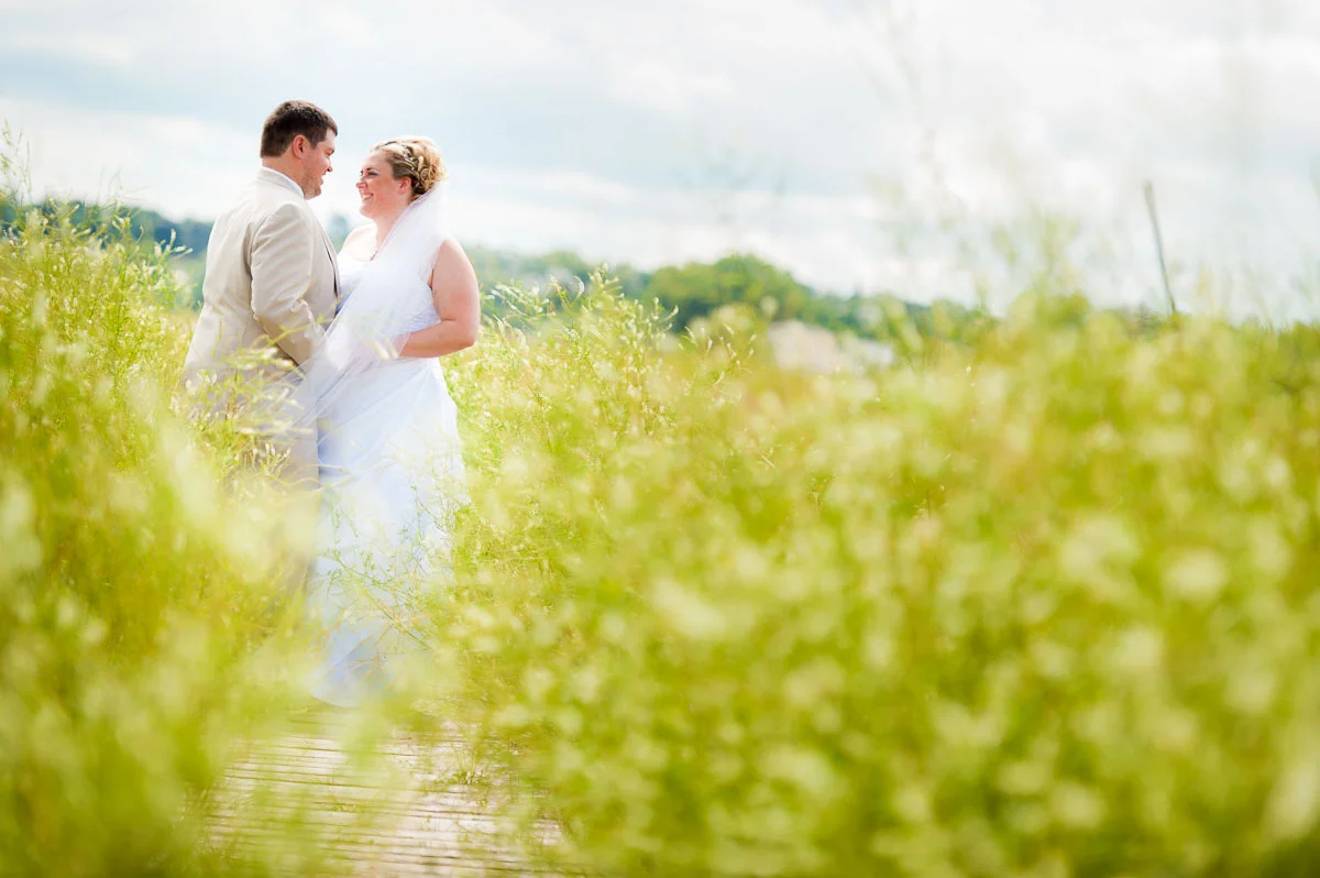Bride & groom embrace amongst the reeds along Lake Michigan during their Blue Harbor Resort wedding. 