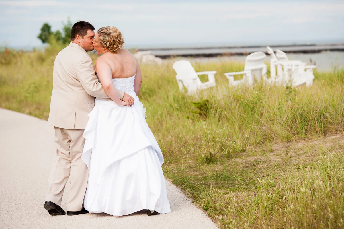 Bride & groom share a kiss while walking along the beach at Blue Harbor Resort. 