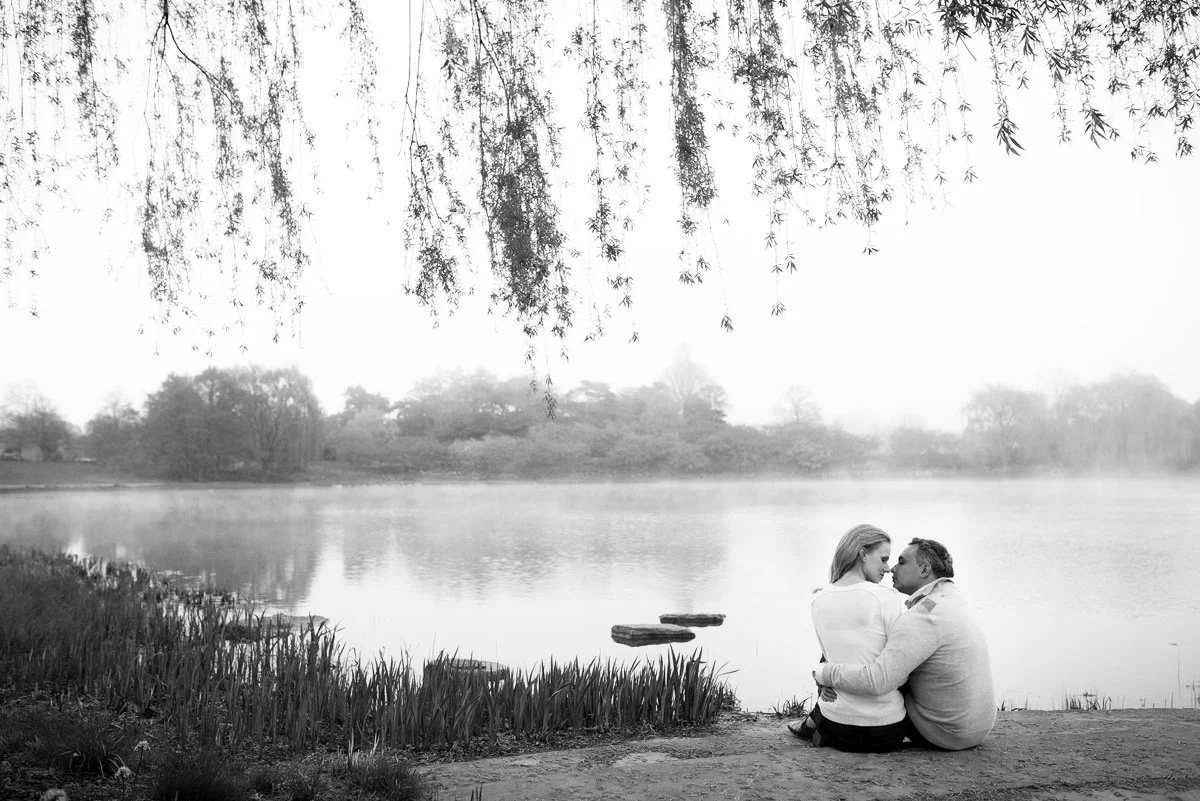 The couple embraces near a foggy lake during their engagement session at the Chicago Botanic Gardens. 