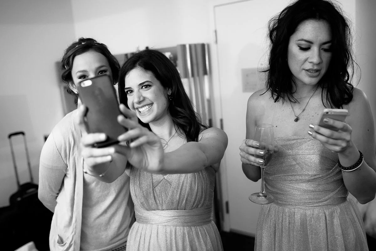 Bridesmaids take selfies on the wedding day at the James Hotel. 