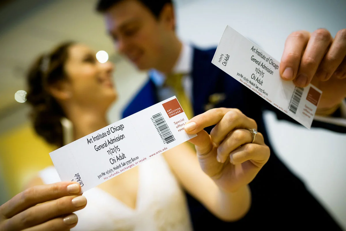 The wedding couple holds up their tickets to the Art Institute of Chicago. 