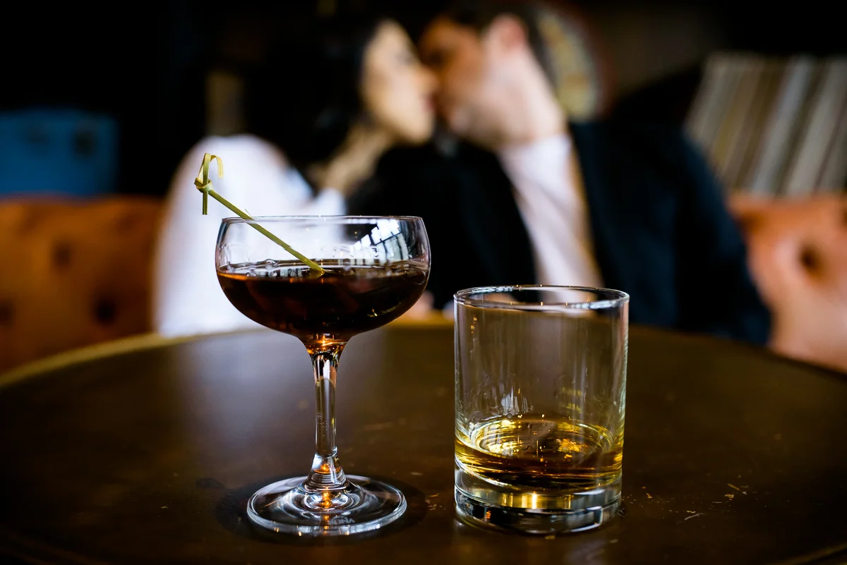 The couple shares a cocktail and a kiss during their Chicago engagement session at The Betty. 