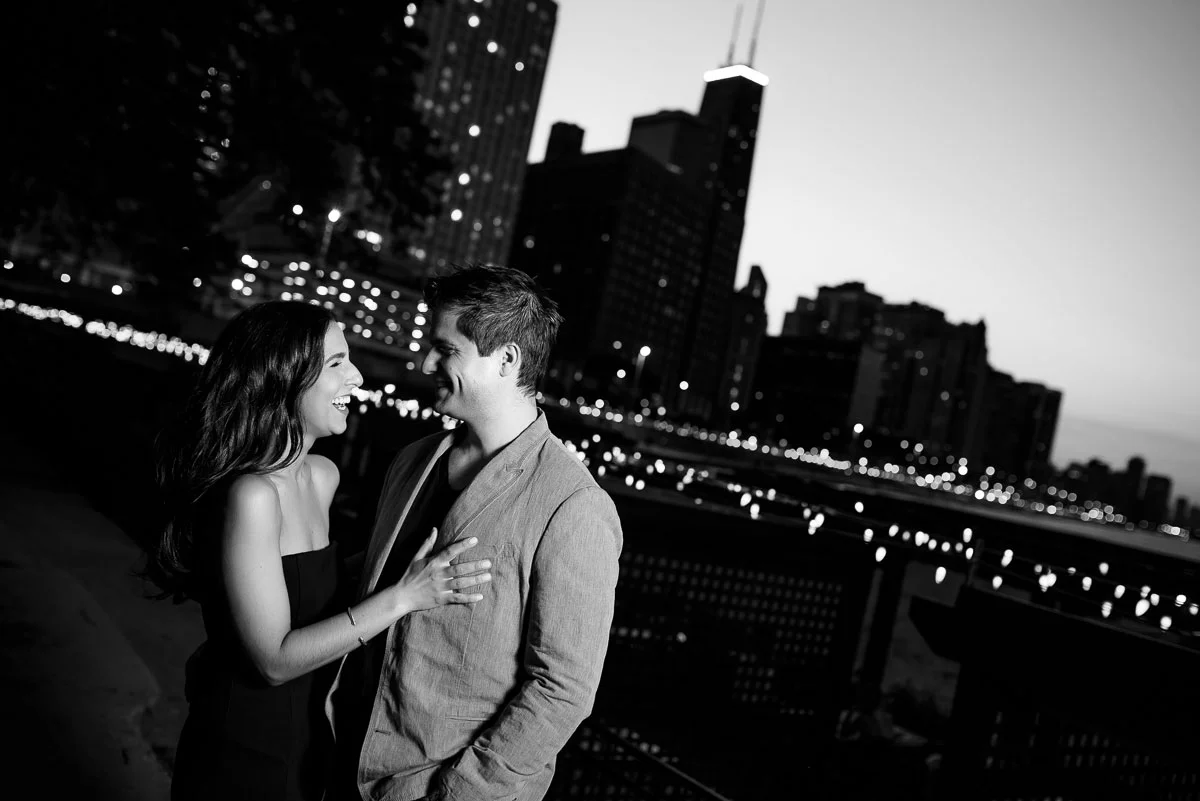 The couple shares a laugh during their Chicago engagement session at Ohio Street Beach at sunset. 