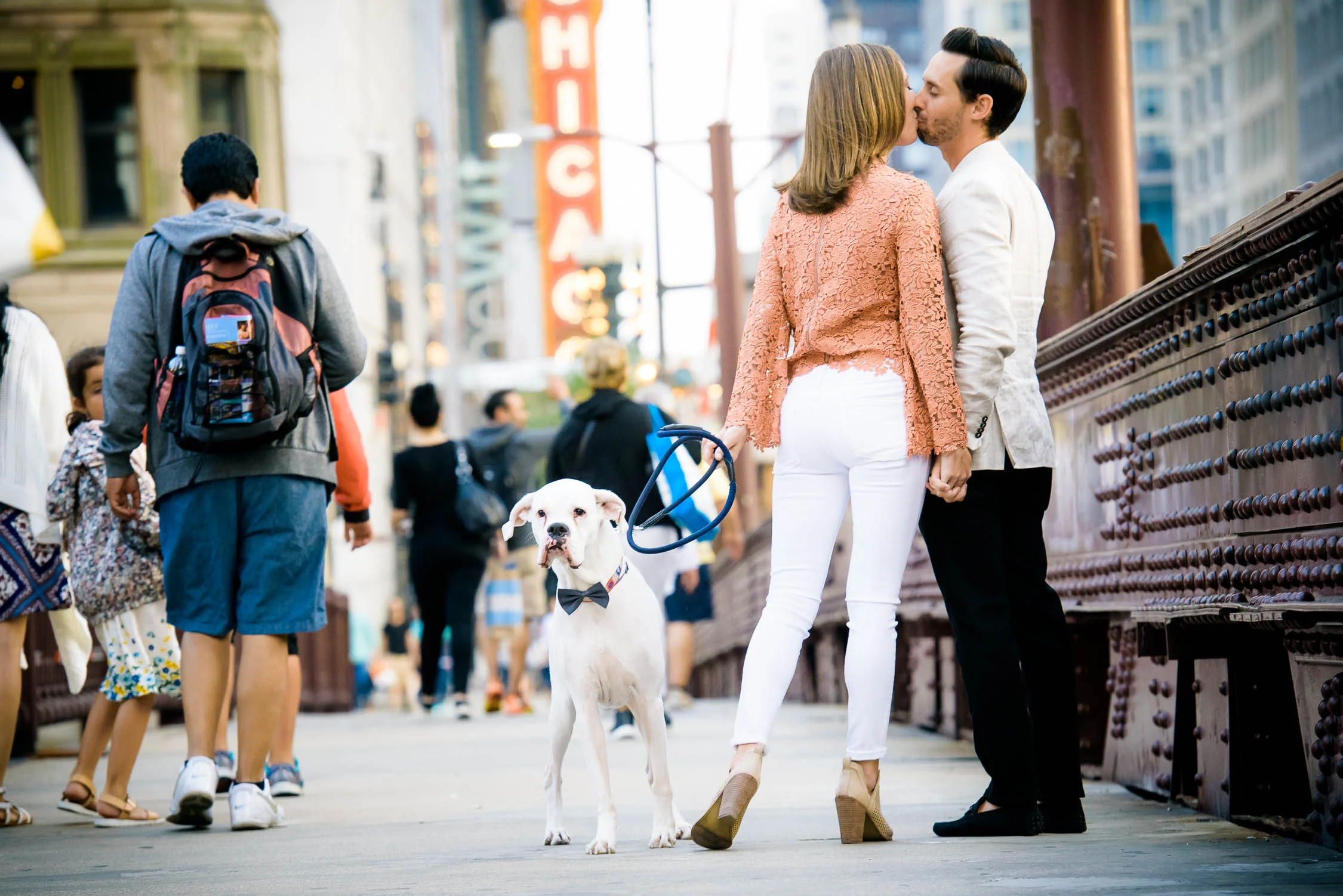 Couple embraces with their dog nearby on the State St. Bridge during their Chicago engagement session. 