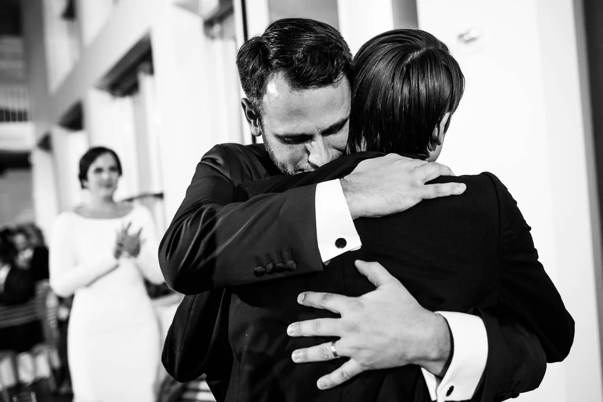 Groom and best man hug after his speech during a winter wedding at the MCA Chicago.