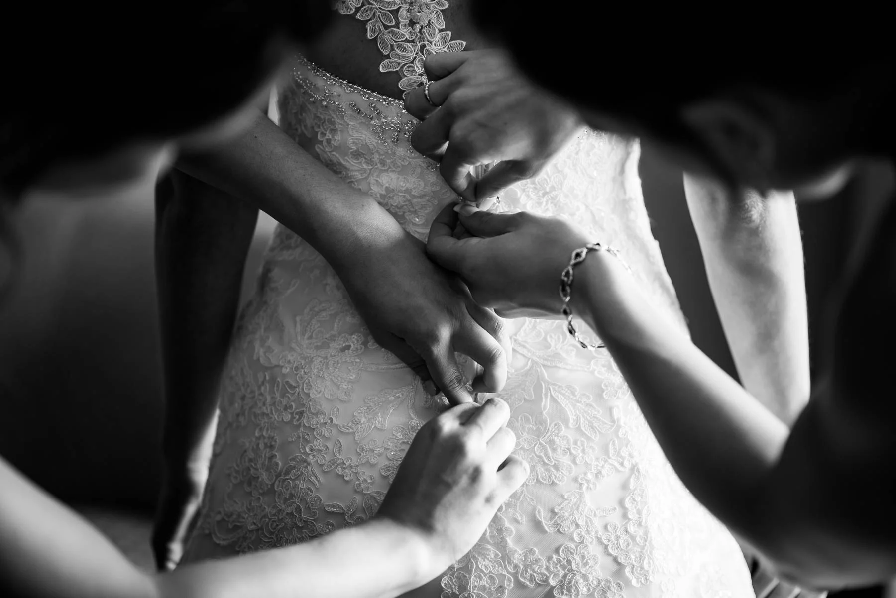 Bridesmaids button up the back of the wedding dress before a St. Charles Country Club wedding
