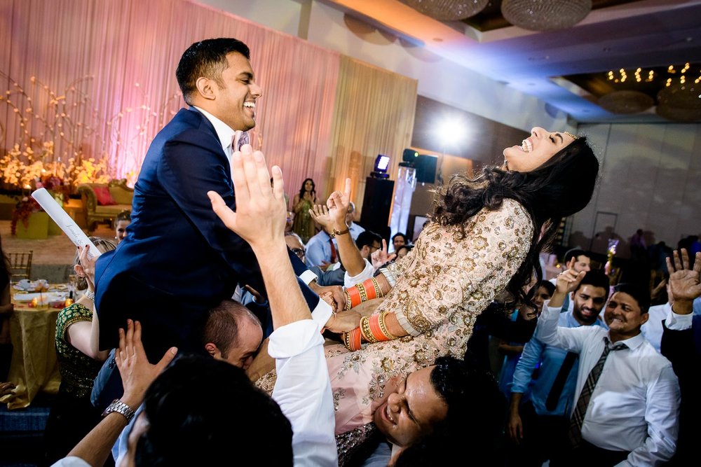 Bride and groom raised in the air during a Renaissance Schaumburg Convention Center Indian wedding reception.