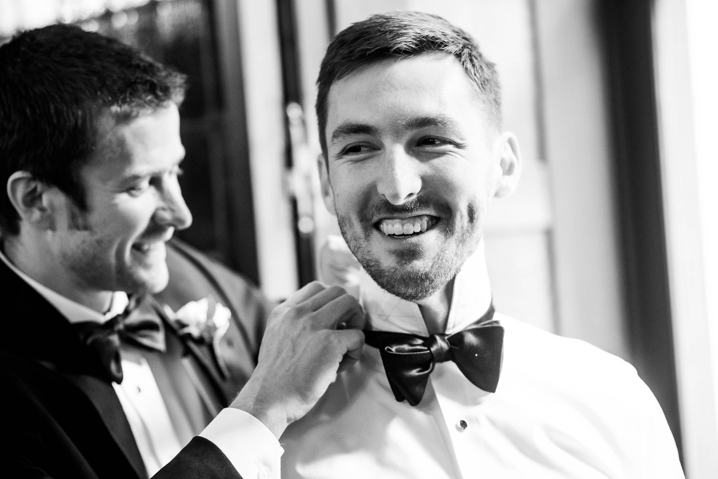 Best man helps the groom with his tie during a Blackstone Chicago wedding.