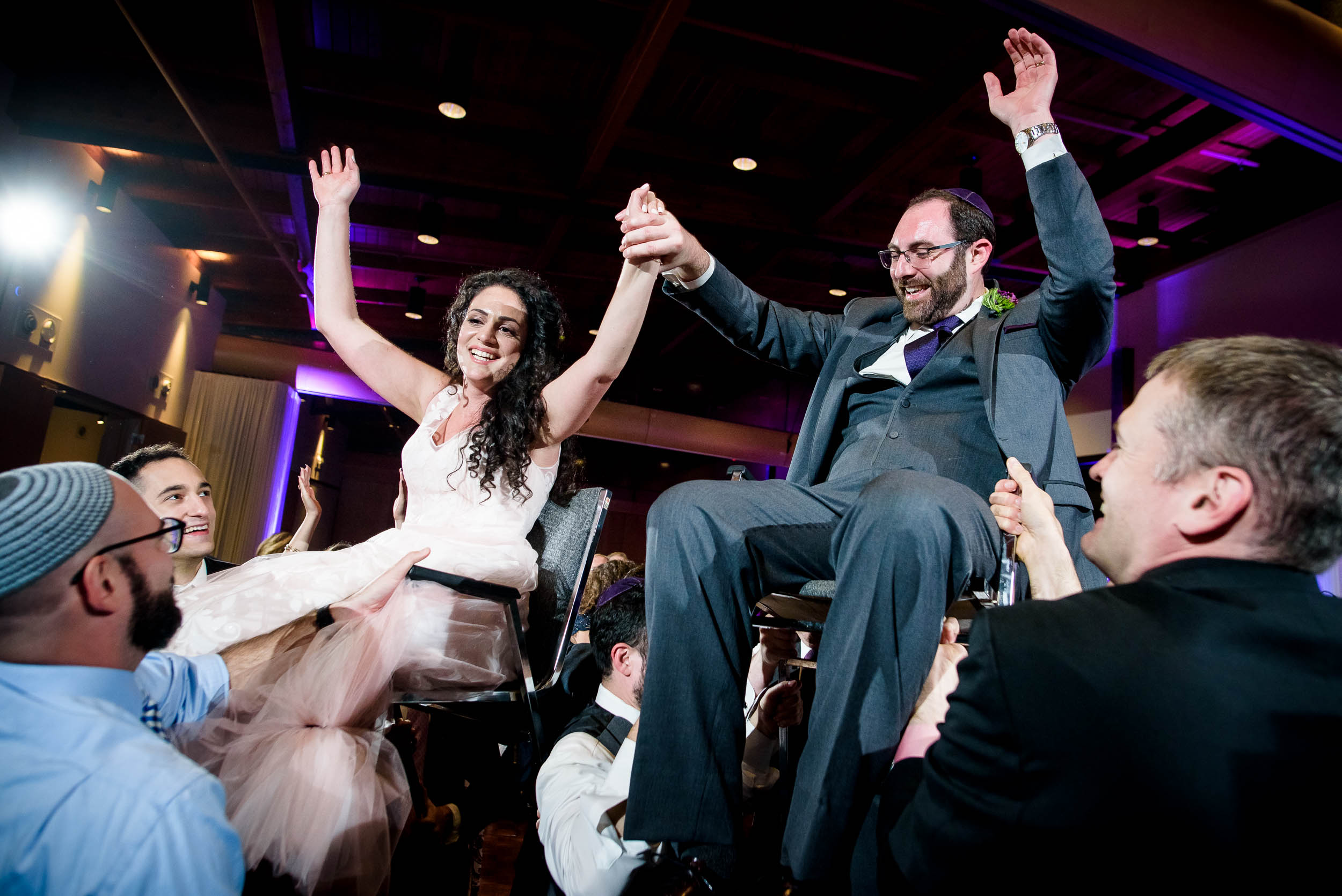Bride and groom up on chairs during the horah during an Independence Grove Chicago wedding.  