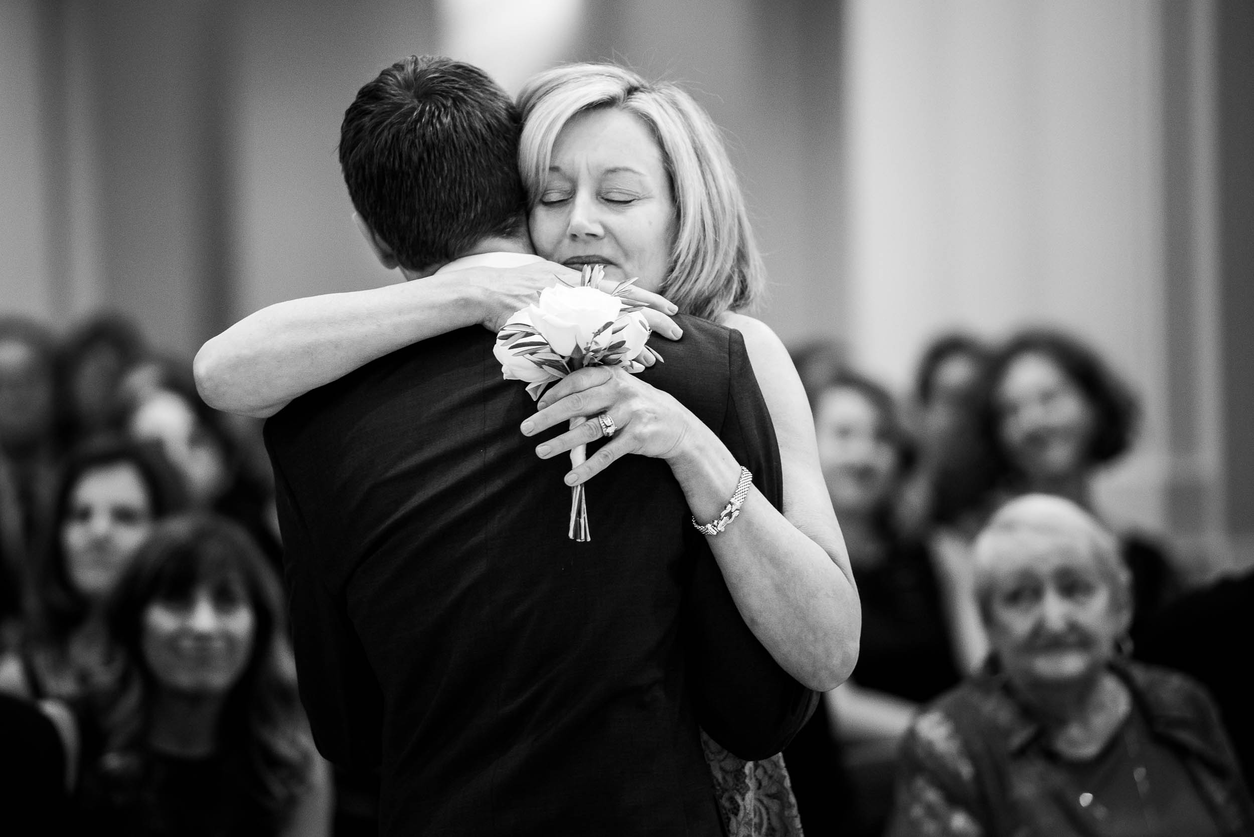 Mother and groom hug during a wedding ceremony at Madonna Della Strada.