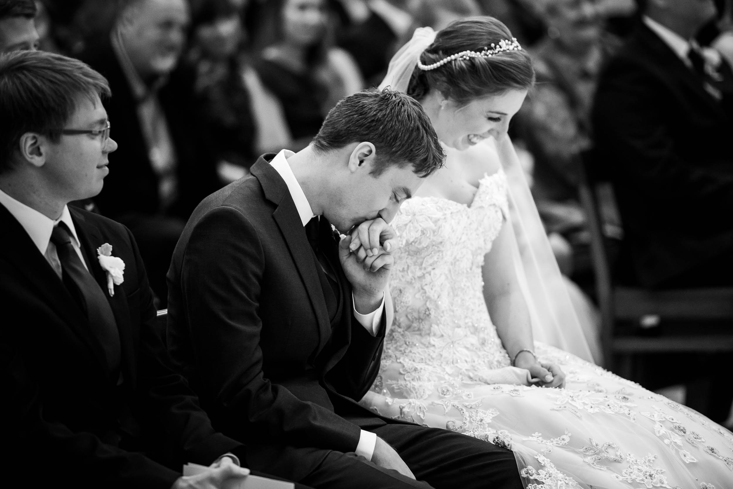 Groom kisses his brides hand during a wedding ceremony at Madonna Della Strada.