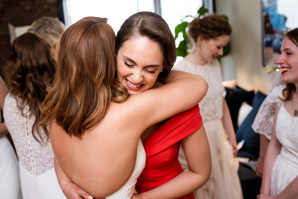 Bride and bridesmaid hugging before ceremony for Carnivale Chicago wedding captured by J Brown Photography