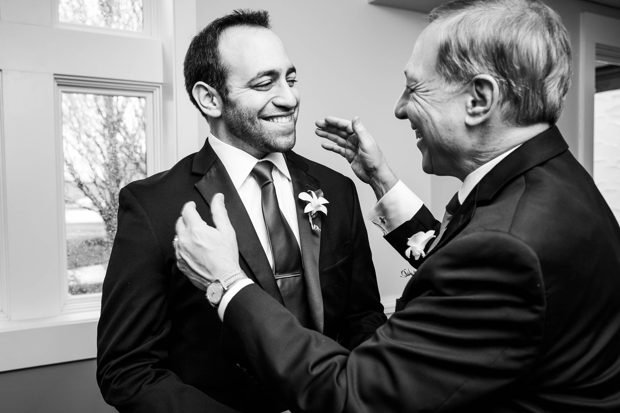 Father and groom embrace during a Chevy Chase Country Club wedding by J. Brown Photography.