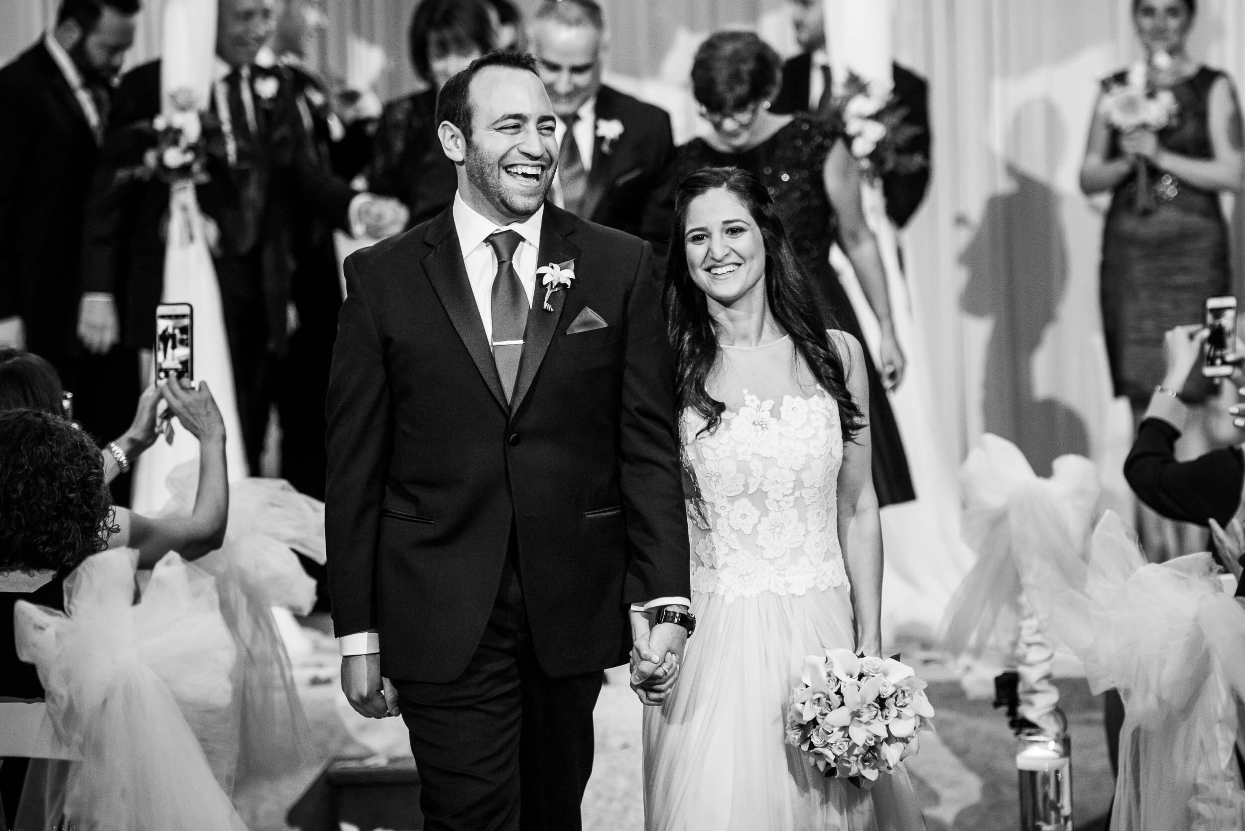 Newly wed bride and groom walk down aisle during a Chevy Chase Country Club jewish wedding by J. Brown Photography.