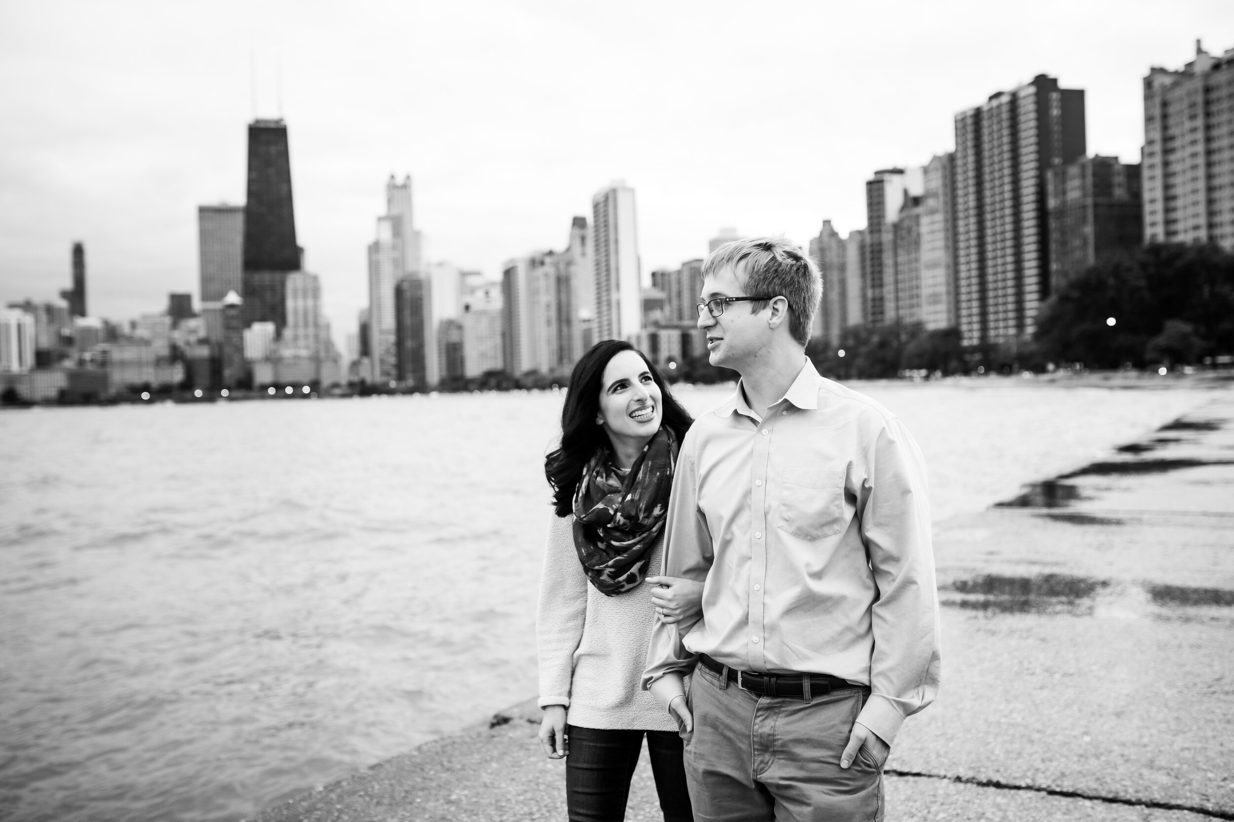 Couple walks along Lake Michigan shore during their Chicago engagement session at North Avenue Beach. 
