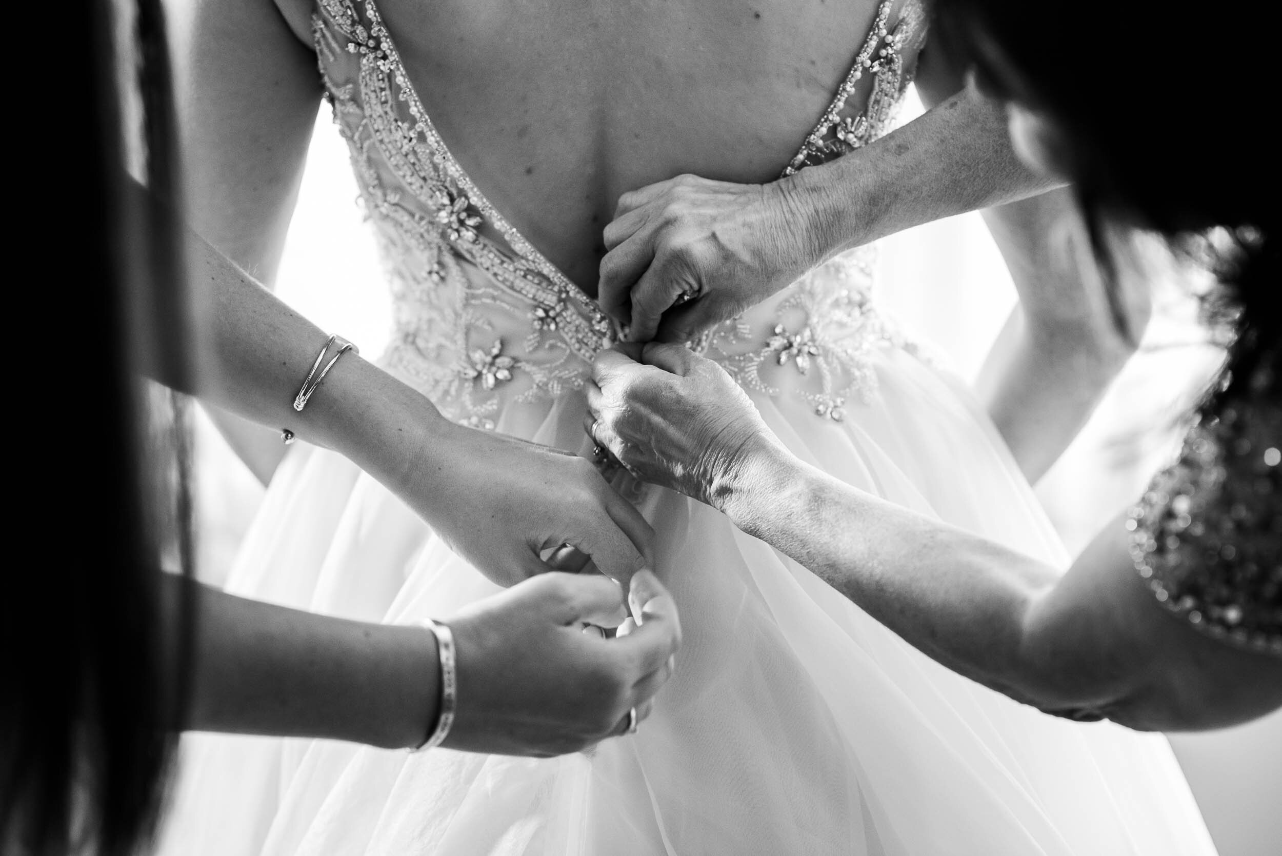 Bridesmaids help bride into her dress: Columbus Park Refectory wedding captured by J. Brown Photography.