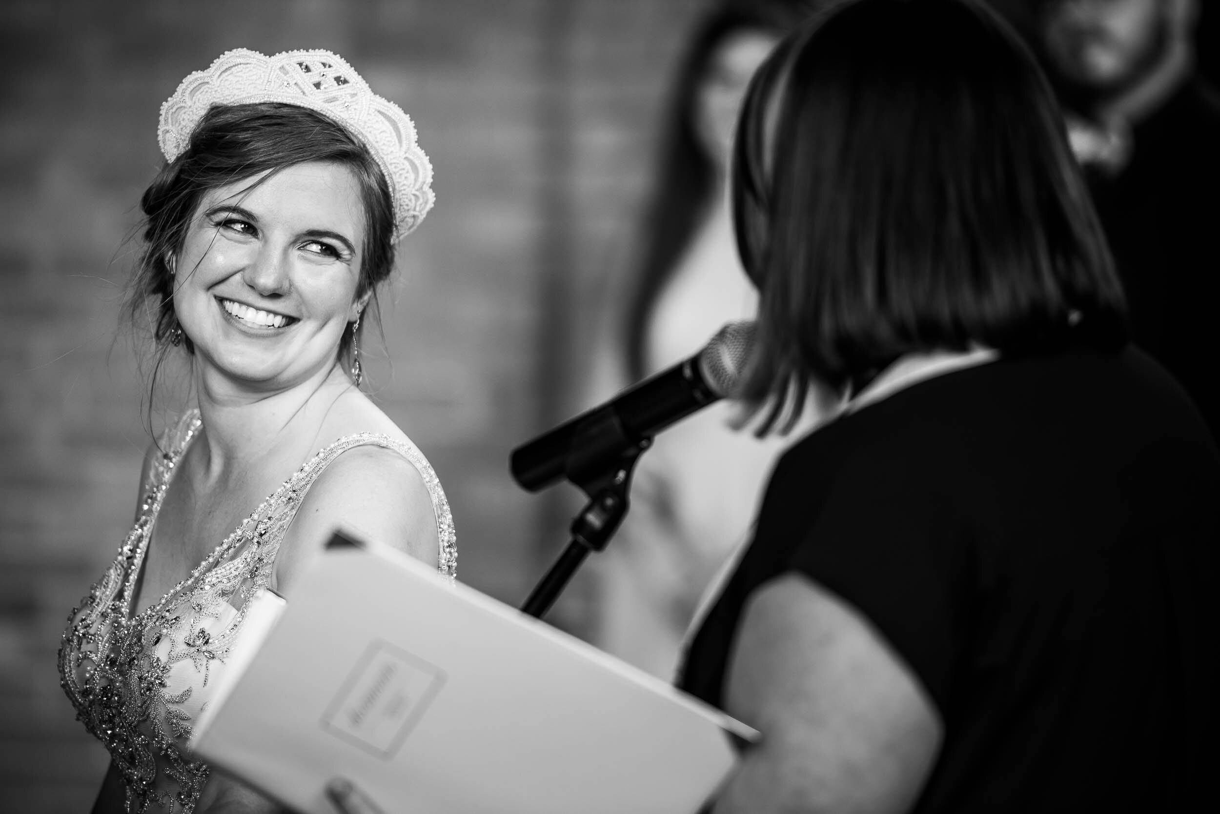 Bride smiles at the officiant and friend during her wedding ceremony: Columbus Park Refectory Chicago wedding captured by J. Brown Photography.