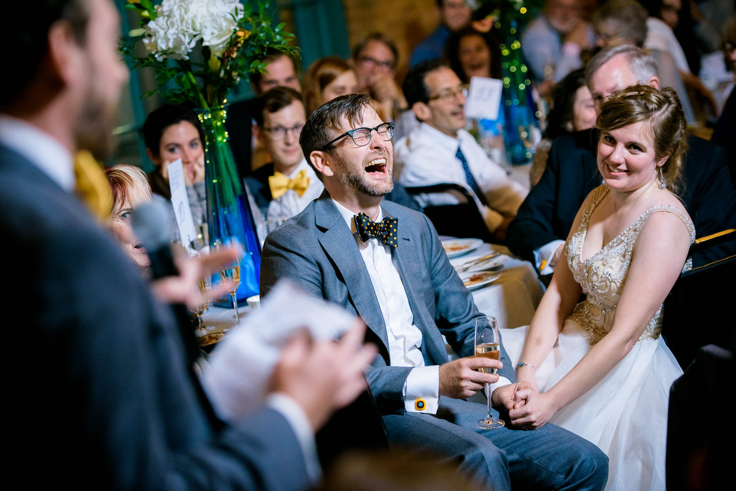 Bride and groom laugh during wedding party toasts: Columbus Park Refectory Chicago wedding captured by J. Brown Photography.